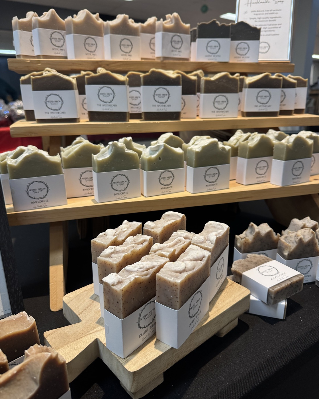 Rows of Nested Arrow soap bars in paper wrap labels on a wooden market rack